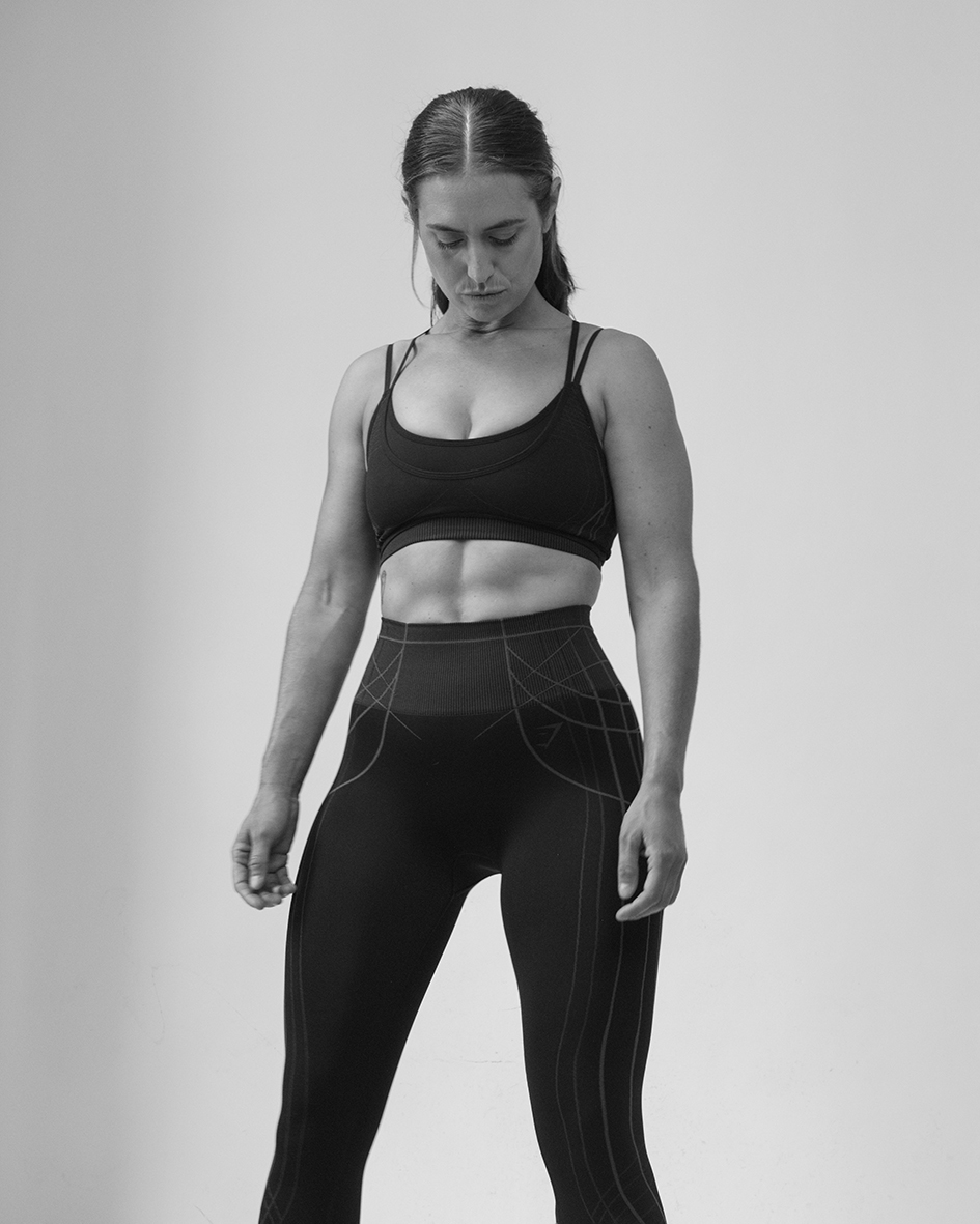 Steph leaning against a wall in bright pink kit